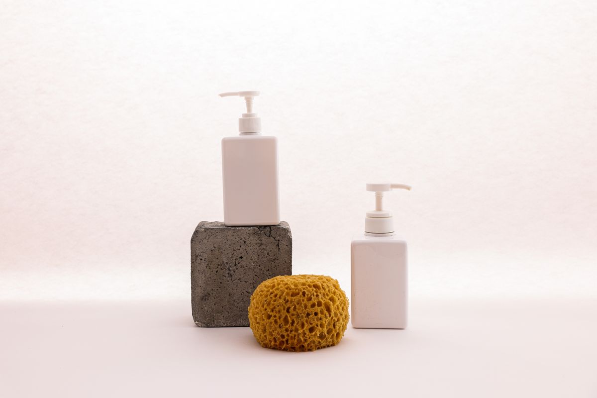A pump dispenser bottle of body wash beside a sponge
