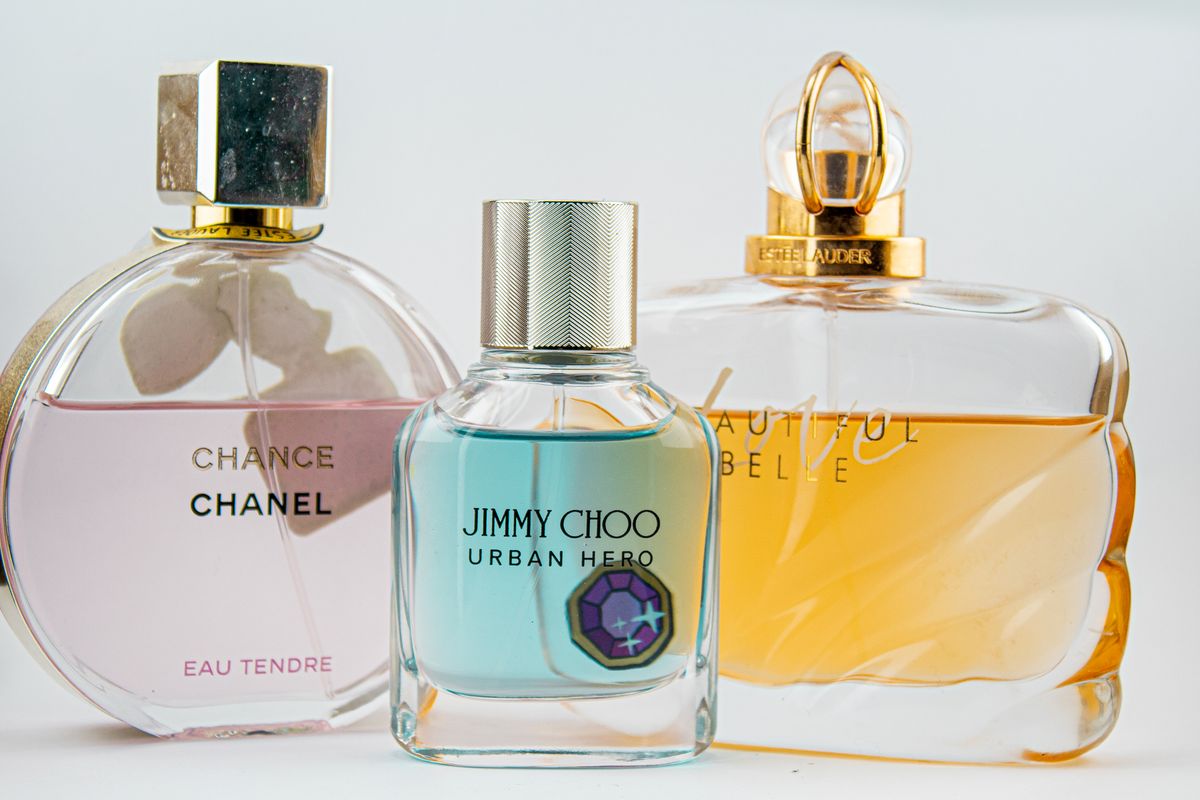 Two perfume bottles side by side in close-up on a neutral surface