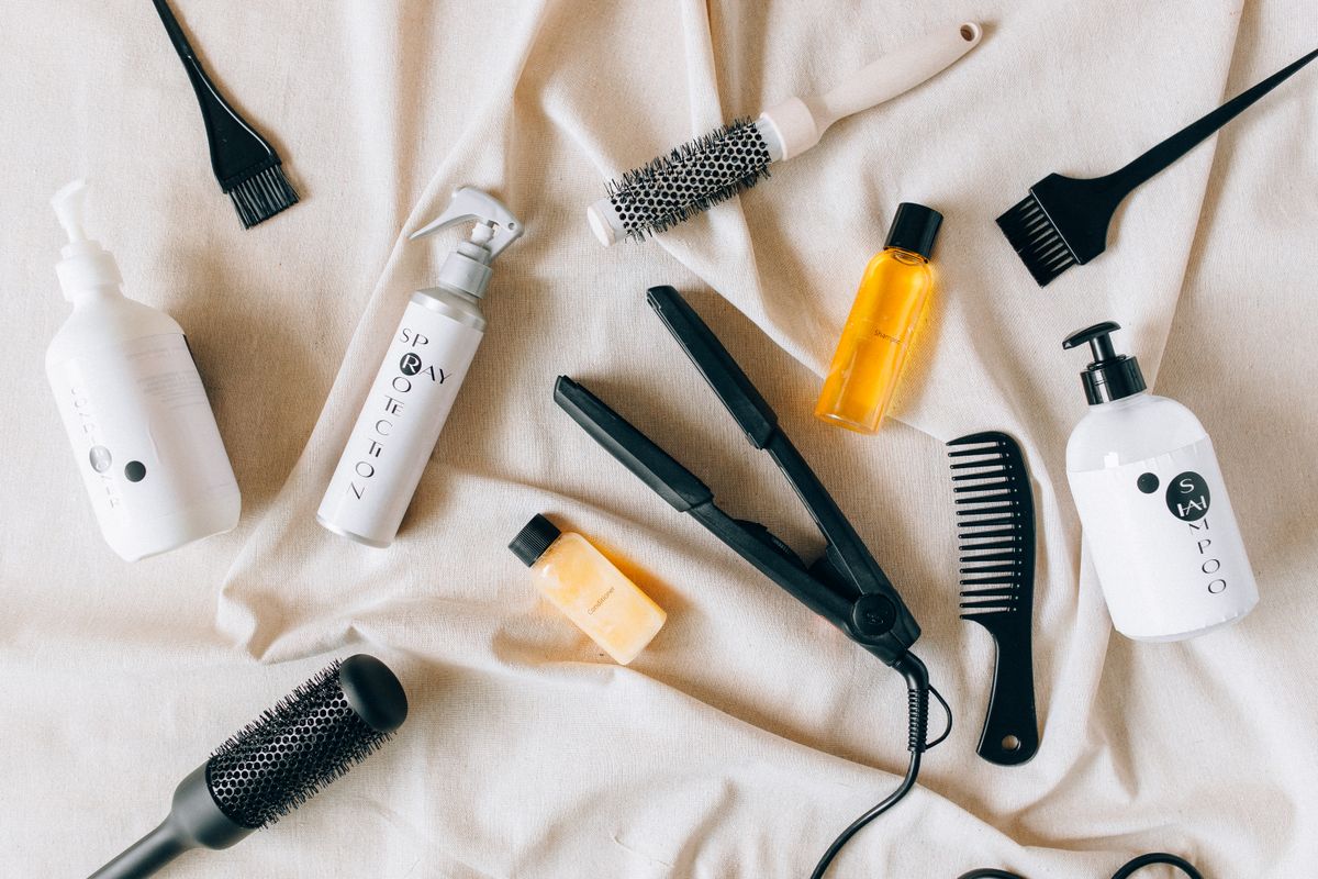 Flat lay of hair styling products and oils on a neutral surface
