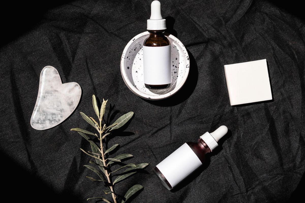 Brown glass skincare bottles beside a gua sha stone