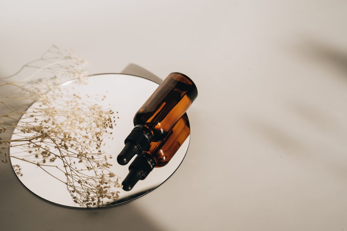 A brown serum bottle on a round mirror with soft lighting