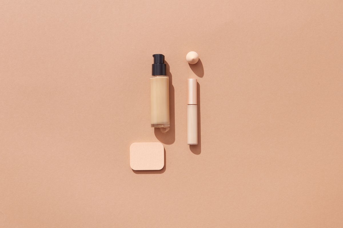 Makeup products and a compact arranged on a brown surface