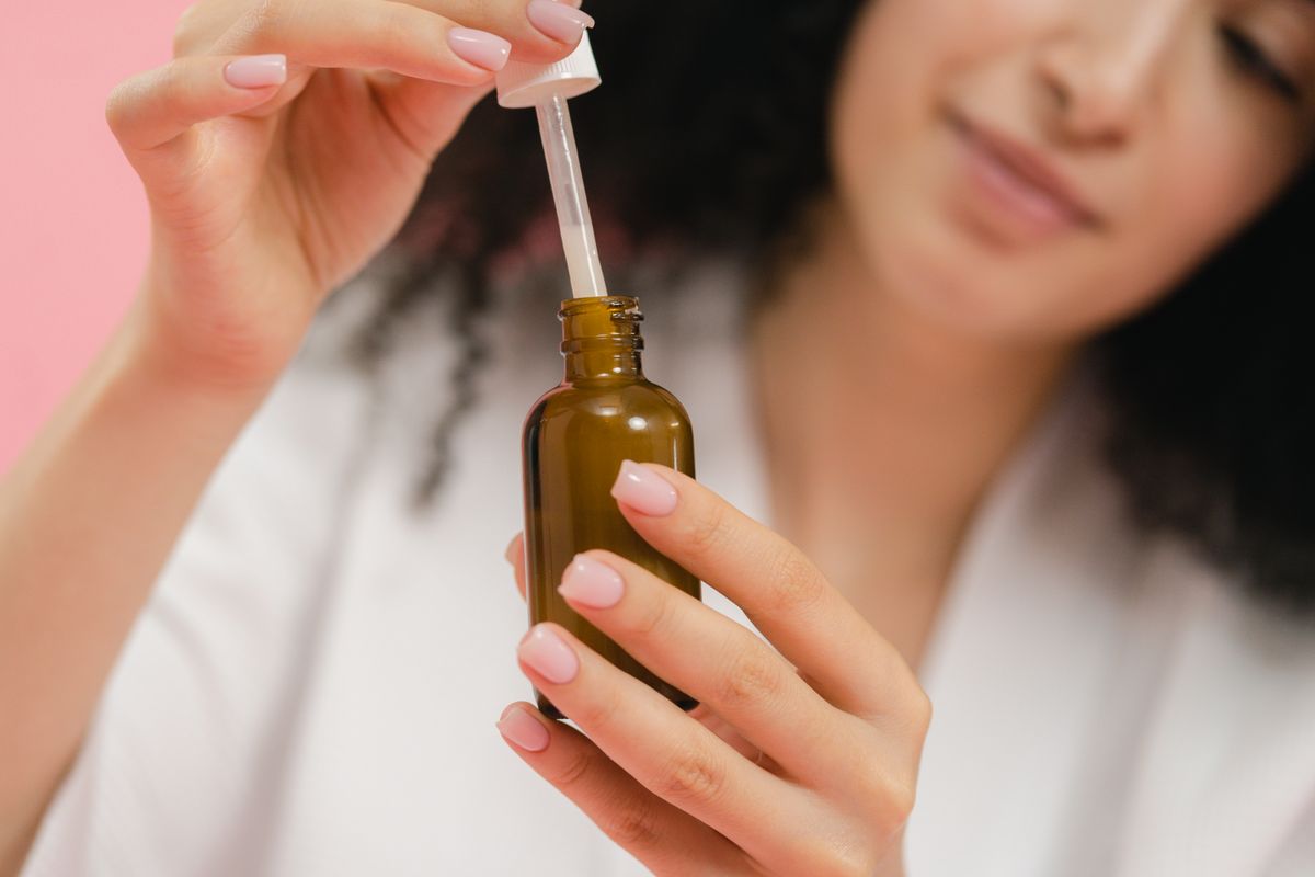 A hand holding a small serum bottle in warm light