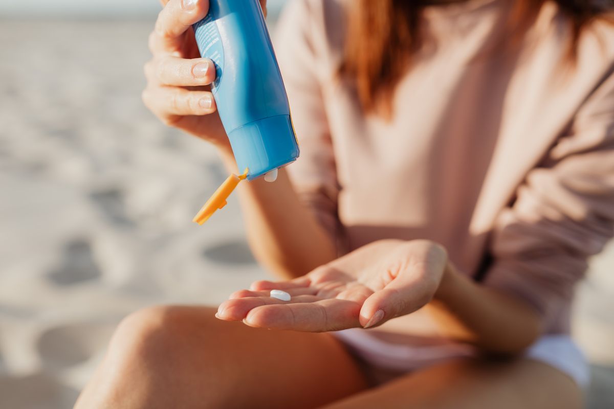 Hands applying sunblock cream from a tube