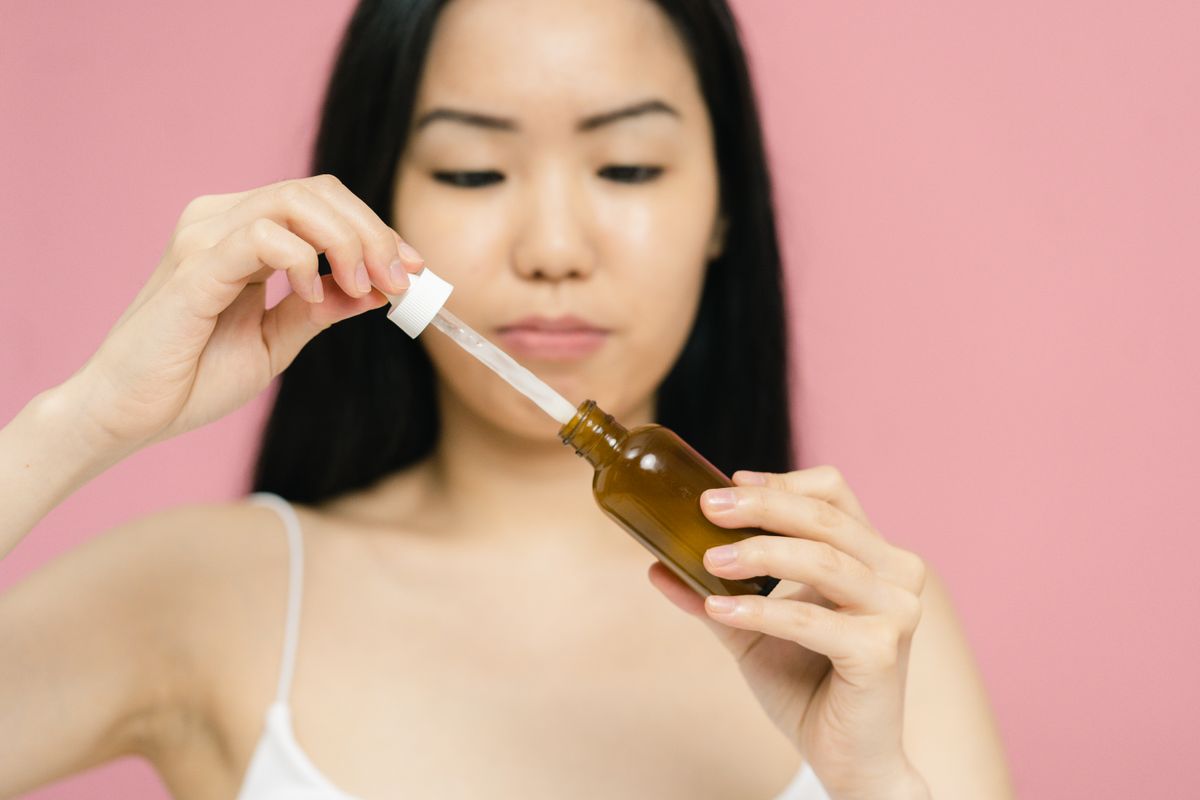 Hand holding a dropper bottle of squalane oil against a soft background